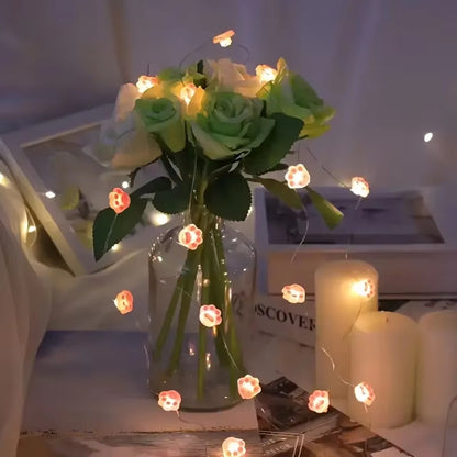 une guirlande LED en forme de pattes de chat roses toutes mignonnes. Elle diffuse une lumière jaune douce et chaleureuse. Idéal pour un coin cocooning.