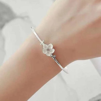 un superbe jonc argenté rigide sur lequel trône une jolie fleur de prunier, un strass rose repose en son coeur.