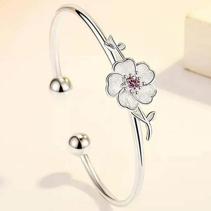 un superbe jonc argenté rigide sur lequel trône une jolie fleur de prunier, un strass rose repose en son coeur.