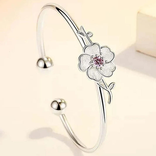un superbe jonc argenté rigide sur lequel trône une jolie fleur de prunier, un strass rose repose en son coeur.