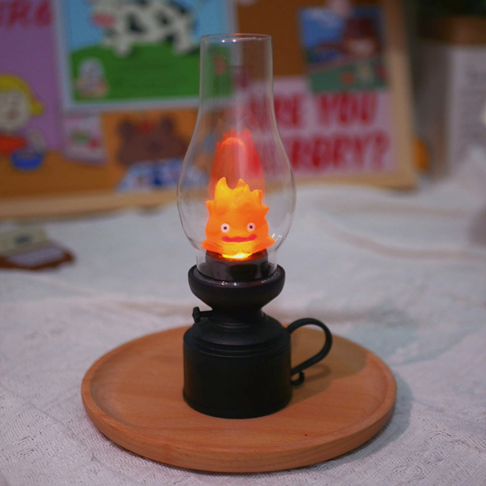 une veilleuse façon vieille lampe à huile dans laquelle se trouve Calcifer, le petit être démoniaque du château ambulant. Enfermé à l'intérieur de cette lampe, il s'allume et éclaire doucement la pièce créant une ambiance apaisante et chaleureuse.