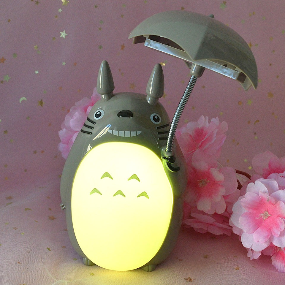 une merveilleuse lampe en forme de Totoro qui tient son parapluie.Il a son célèbre sourire et la lumière peut être allumée sous son parapluie ou sur son ventre