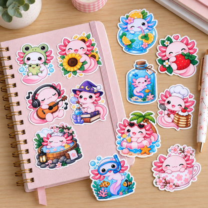 Lot de stickers kawaii axolotl roses et colorés, certains collés sur un carnet à spirales rose pastel, d’autres posés sur un bureau en bois. Illustrations mignonnes sur les thèmes de la magie, des fleurs, de la musique et de l’été, idéales pour décorer carnets, agendas et journaux.