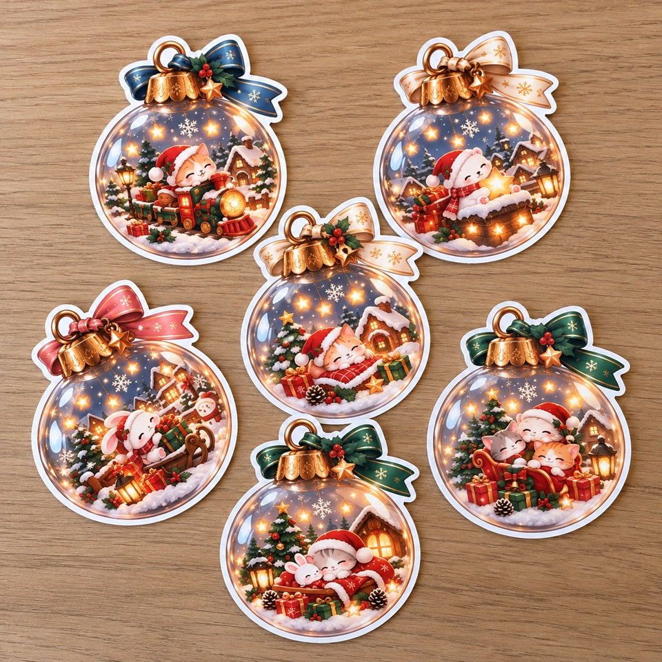 Lot de 6 stickers kawaii de Noël en forme de boules de sapin, illustrés de chats et lapins adorables avec bonnets de Noël, petit train, traîneau, cadeaux et villages enneigés. Autocollants festifs aux rubans colorés, parfaits pour décorer cartes de vœux, emballages cadeaux, carnets et créations DIY.
