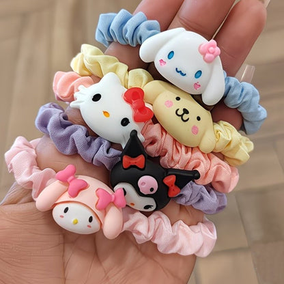 Lot de cinq élastiques à cheveux kawaii inspirés de l'univers Sanrio, avec les personnages Cinnamoroll, Hello Kitty, Kuromi, My Melody et Pompompurin. Les chouchous sont confectionnés dans un tissu satiné aux couleurs pastel rose, bleu, violet et jaune. Ils sont tenus dans une main. Idéals pour ajouter une note kawaii à votre style.