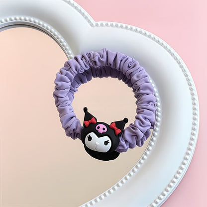 Un joli élastique à cheveux kawaii inspirés de l'univers Sanrio, avec le personnage Kuromi. Le chouchou est confectionné dans un tissu satiné aux couleurs pastel violet. Présenté sur une surface élégante, il est idéal pour ajouter une note kawaii à votre style.