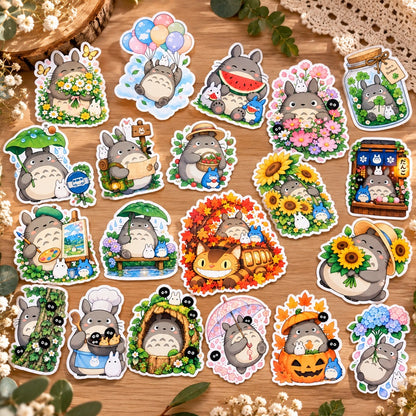 Lot de stickers Totoro kawaii colorés avec fleurs, tournesols, scènes de pluie et d’automne, présentés dans un joli décor naturel sur fond en bois.