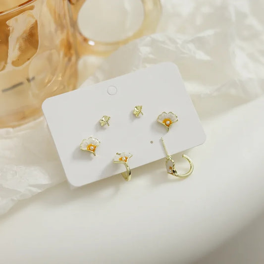 un lot de 3 paires de boucles d'oreilles en forme de feuille de gingko. Finition dorée et perles blanches au centre de la feuille