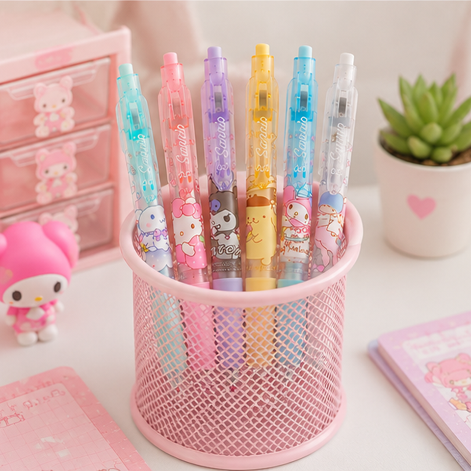 Lot de 6 stylos rétractables Sanrio pastel rangés dans un pot à crayons en métal rose, personnages kawaii Hello Kitty, My Melody, Cinnamoroll, Pompompurin et Kuromi, décor bureau avec plante succulente, figurine My Melody et mini commode à tiroirs roses