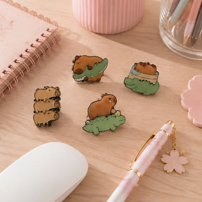 Des magnets kawaii représentant un capybara et un crocodile sont posés sur un bureau entourés d'article de papeterie divers et mignons.