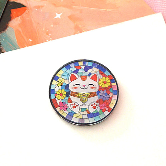 un magnet rond représentant un maneki neko blanc ans une mosaique colorée