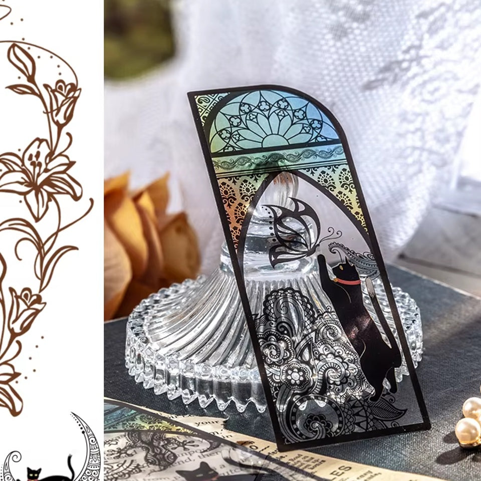 des marque-pages façon vitrail coloré orné de papillons ou de lunes. Un adorable chat noir se trouve devant. L'ensemble est mystérieux et magique.