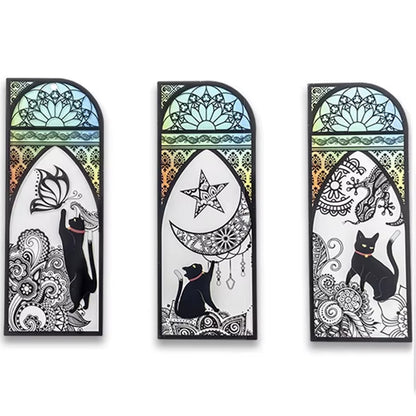 des marque-pages façon vitrail coloré orné de papillons ou de lunes. Un adorable chat noir se trouve devant. L'ensemble est mystérieux et magique.