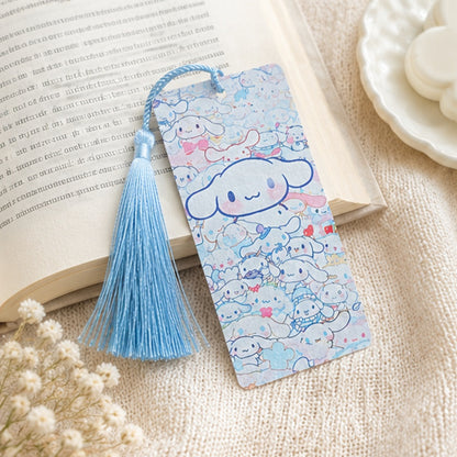 Marque-page kawaii Cinnamoroll bleu avec pompon assorti, présenté sur un livre ouvert dans une ambiance douce et cosy. Accessoire de lecture Sanrio mignon aux couleurs pastel.