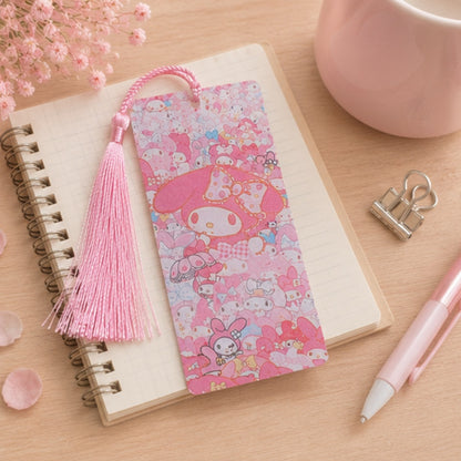 Marque-page kawaii My Melody rose avec pompon assorti, présenté sur un carnet dans un décor pastel. Accessoire de lecture Sanrio mignon et original pour accompagner livres et romans.