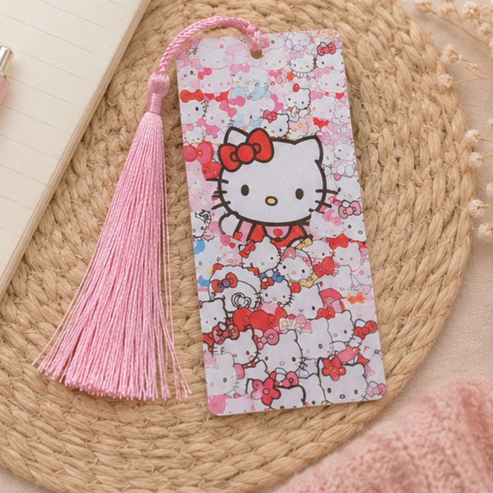 Marque-page kawaii Hello Kitty rouge et blanc avec pompon rose, présenté dans un décor doux avec carnet et accessoires pastel. Accessoire de lecture Sanrio mignon et coloré.