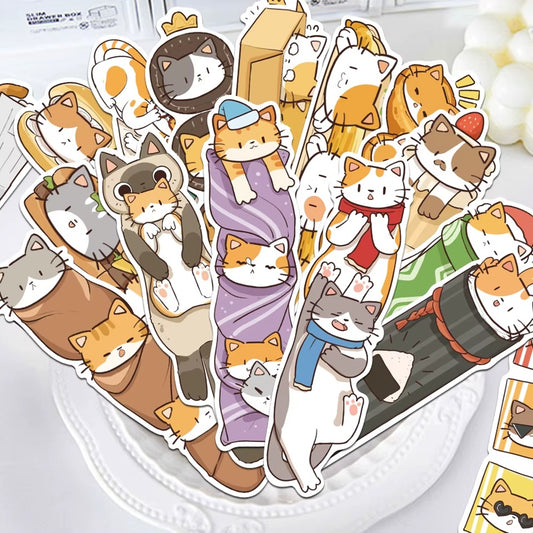 des marques-pages cartonnés représentant des chats bruns, roux et gris dans de situations cocasses et rigolotes Ils sont posés sur une assiette sur une table légèrement décorée.