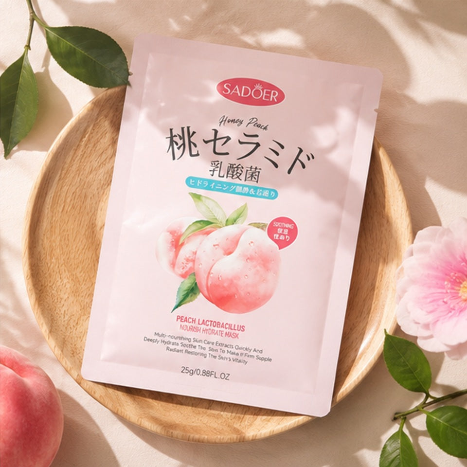 Masque en tissu hydratant à la pêche SADOER présenté sur un plateau en bois, entouré de feuilles vertes et d'une fleur rose. L'ambiance est douce et lumineuse, avec des ombres naturelles et des tons beige et rose évoquant un moment de bien-être.