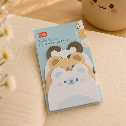 Bloc de sticky notes ours kawaii BuBu Bears présenté sur un carnet ouvert, dans une ambiance papeterie douce et lumineuse avec petites fleurs.