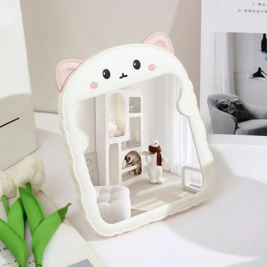 un adorable miroir rose à poser sur une table ou une coiffeuse. Il a des petites oreilles de chat et une expression hyper kawaii. C'est un élément de décoration hyper mignon.