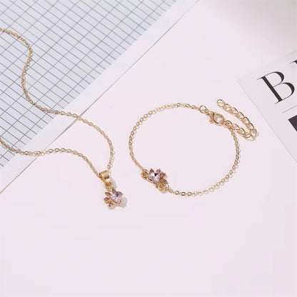 une parure de bijoux composée d'un collier, d'un bracelet, d'une bague et de boucles d'oreilles en forme de patte de chat tout en strass rose.