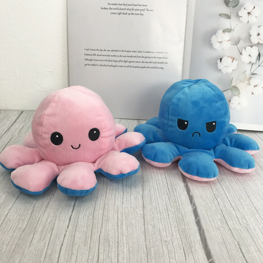 une peluche en forme d'octopus réversible. Elle a deux couleurs : bleu et rose, et on peut la retourner pour montrer notre expression : heureuse ou plutôt fâchée
