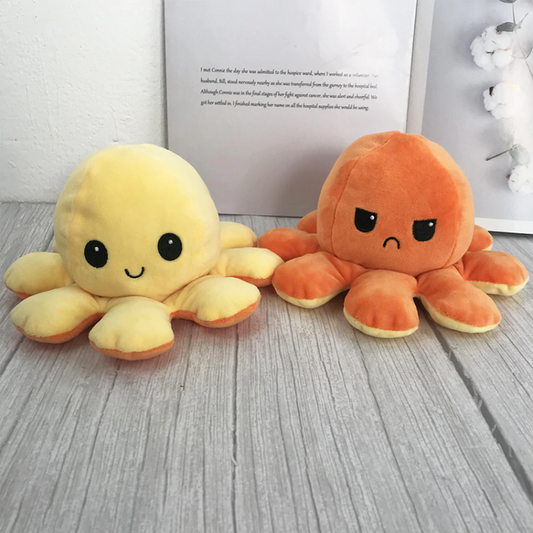 une peluche en forme d'octopus réversible jaune et orange qui exprime deux émotions différentes : d'un côté, l'expression heureuse et joyeuse puis quand on le retourne, une expression boudeuse.