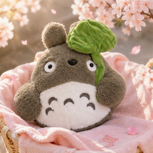 Peluche Totoro kawaii tenant sa feuille verte sous des fleurs de sakura, ambiance printanière 🌸