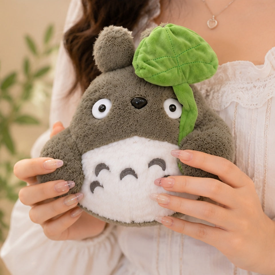 Peluche Totoro kawaii toute douce tenue dans les mains, avec adorable feuille verte sur la tête et détails brodés mignons ✨ Peluche moelleuse inspirée d’un univers japonais féerique, parfaite pour décorer une chambre cosy, offrir un cadeau adorable ou accompagner les moments cocooning.