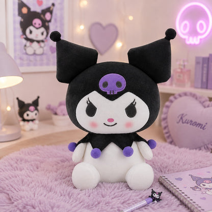 Peluche Kuromi kawaii noire et blanche avec tête de mort violette et pompons colorés, présentée dans un joli décor de chambre pastel rose et lilas.