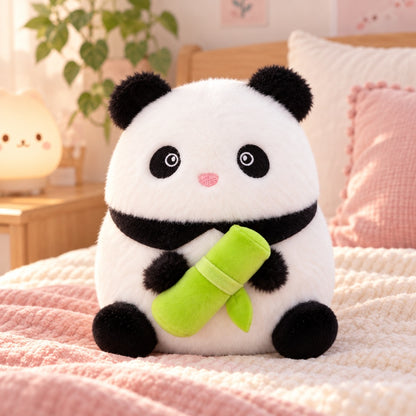 Peluche panda kawaii noire et blanche tenant un bambou vert, installée sur un lit dans une jolie chambre pastel rose, douce et cosy.