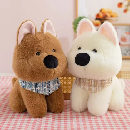 Deux adorables peluches chien marron et blanc toutes douces avec foulard bleu et beige à carreaux, installées sur une nappe rouge et blanche dans une ambiance calme et lumineuse.