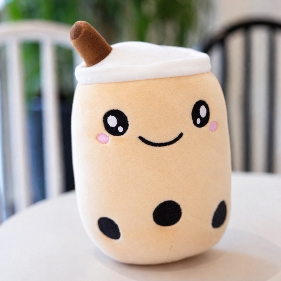 Peluche kawaii en forme de bubble tea couleur beige crème pastel, avec un adorable visage souriant, de grands yeux brillants, des joues roses et trois perles de tapioca noires. Son design tout doux représente un gobelet de thé aux perles avec un couvercle blanc et une petite paille marron. Posée sur une table claire dans un décor chaleureux, cette peluche boba moelleuse et mignonne est idéale pour décorer une chambre, offrir un cadeau original ou compléter une collection de peluches kawaii.