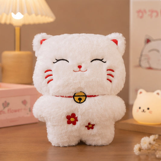Peluche Maneki Neko blanche ultra douce avec visage brodé souriant, clochette dorée et petites fleurs rouges, inspirée du célèbre chat porte-bonheur japonais. Peluche kawaii moelleuse idéale pour les câlins et une décoration cocooning japonaise.