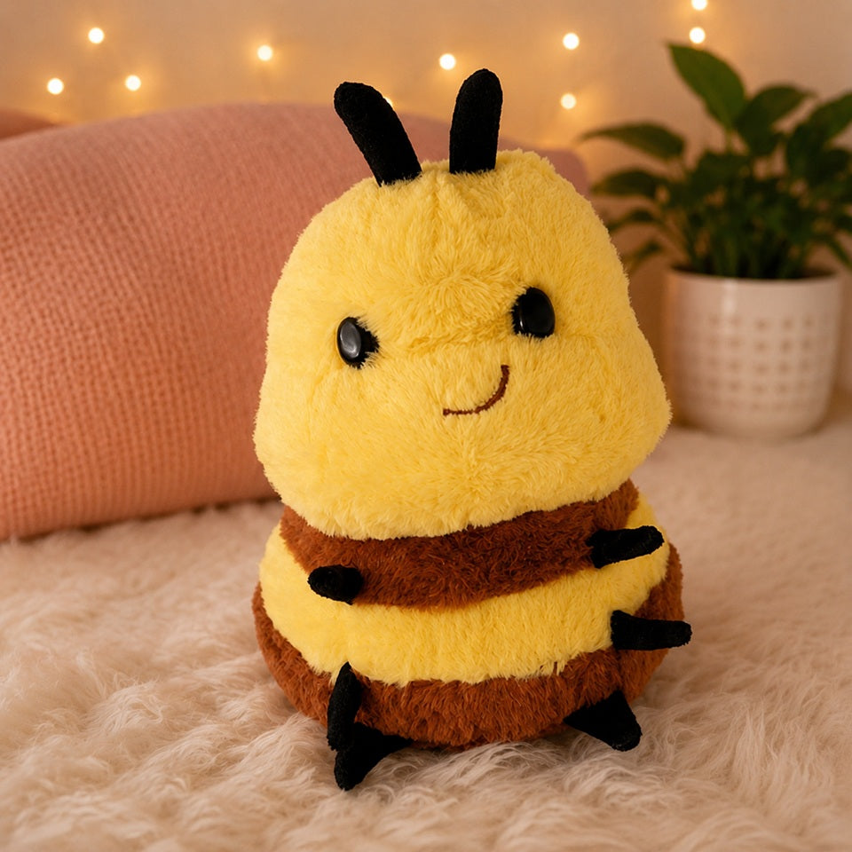 Peluche abeille kawaii jaune et marron dans un décor cosy avec coussin rose et guirlande lumineuse.