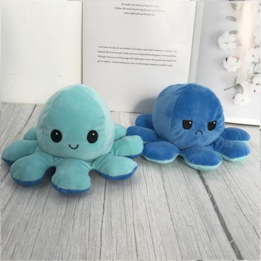 une peluche en forme d'octopus réversible bleue qui exprime deux émotions différentes : d'un côté, l'expression heureuse et joyeuse puis quand on le retourne, une expression boudeuse.
