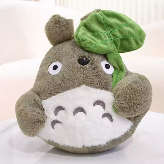 une adorable peluche Totoro qui tient une feuille dans sa main. Adorable et tellement douce, elle est parfaite pour de gros câlins et pour tous les fans.