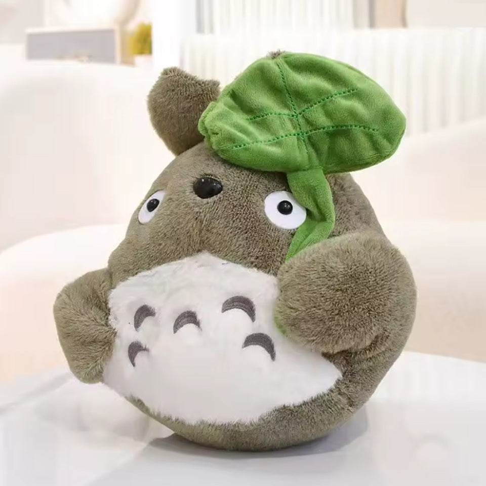 une adorable peluche Totoro qui tient une feuille dans sa main. Adorable et tellement douce, elle est parfaite pour de gros câlins et pour tous les fans.