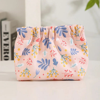 Petite pochette de rangement rose à motifs floraux colorés, idéale pour organiser câbles, chargeurs et petits accessoires électroniques, présentée sur une table blanche.