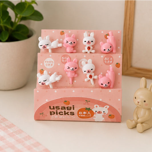 Lot de 8 pics alimentaires kawaii en forme de petits lapins roses et blancs, présentés dans leur emballage rose Usagi Picks.