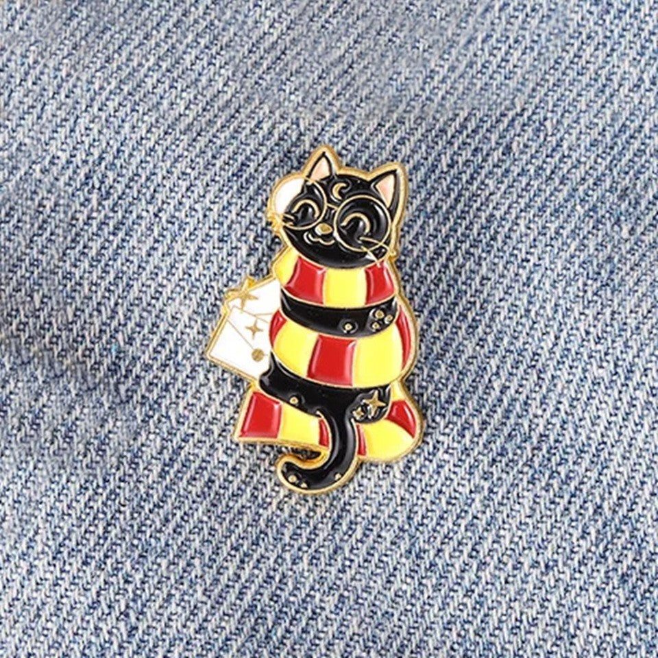 un pin's en forme de chat noir qui porte des lunetes rondes et l'écharpe de la maison gryffondeor de Poudlard.