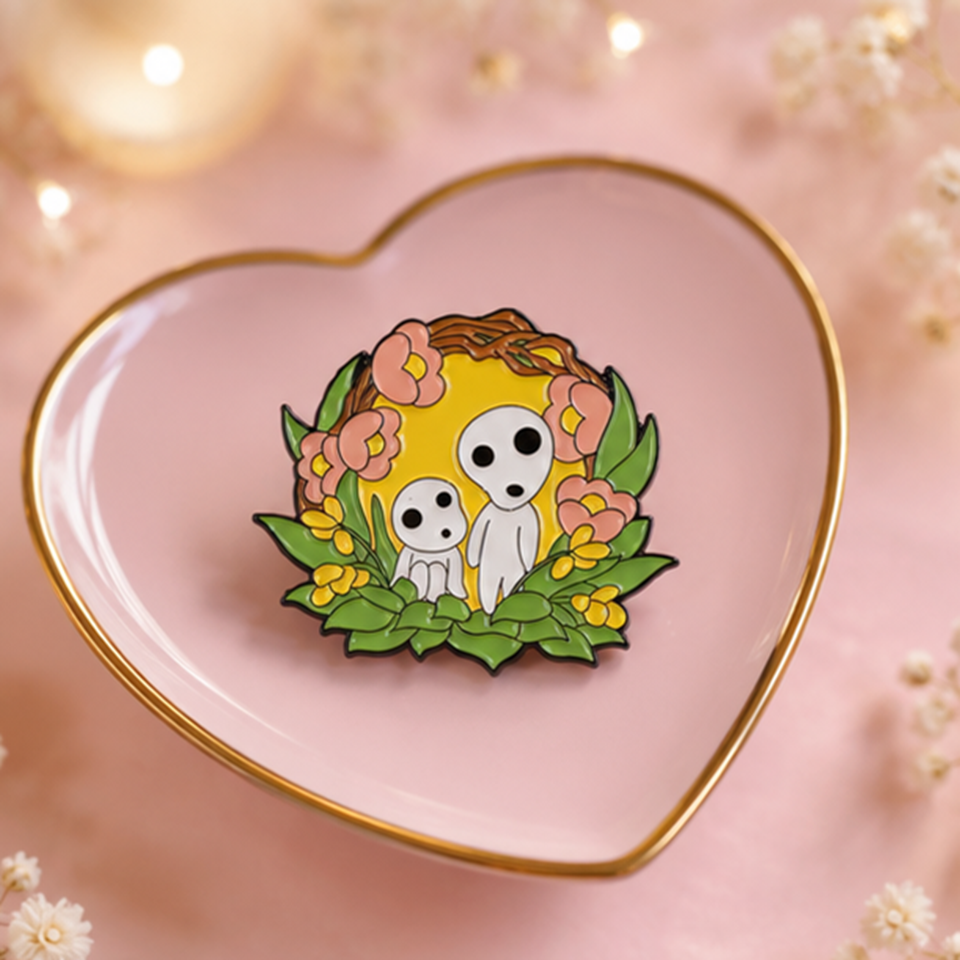 un joli pin's représentant des kodamas, petits êtres mystérieux de la fôret. ils sont dans un décor fleuri et nature