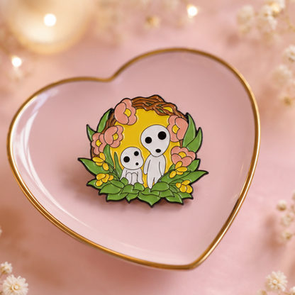 un joli pin's représentant des kodamas, petits êtres mystérieux de la fôret. ils sont dans un décor fleuri et nature