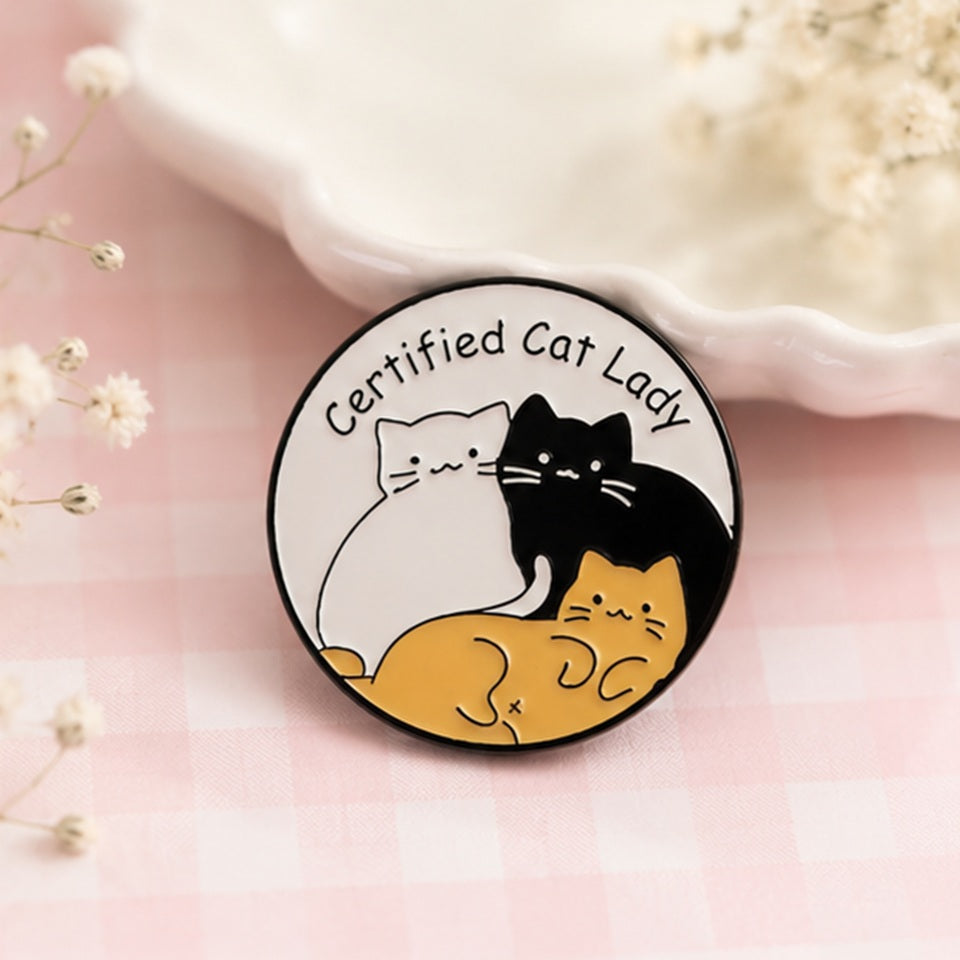 Pin's la dame aux chats kawaii porté sur une veste, accessoire humour et douceur féline ✨