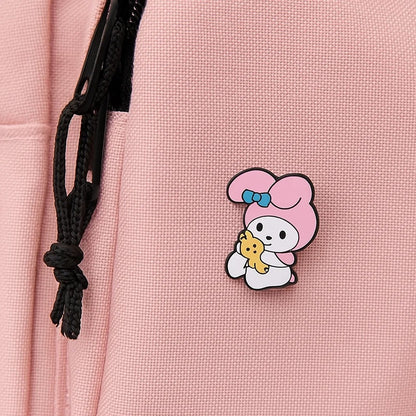 un pin's au design du personnage My Melody de Sanrio. Identifiable grâce à ses longues oreilles roses, il est ici dans une pose trop mignonne avec un petit ourson en peluche dans les mains.