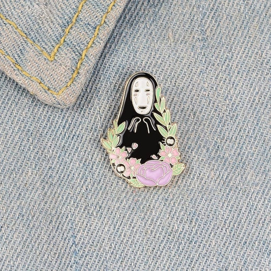 un joli pin's représentant Sans Visage, le personne énigmatique et surprenant du film Le voyage de chihiro. Entouré de fleurs et de noiraudes, il est le symbole de l'acceptation de soi et de la solitude