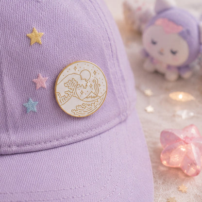 Pin’s vague japonaise minimaliste blanc et doré porté sur une casquette violette pastel ✨ Badge élégant inspiré de la Grande Vague de Kanagawa avec détails raffinés représentant les vagues, le mont Fuji et un ciel étoilé. Parfait pour personnaliser une veste, un sac ou une casquette avec une touche japonaise chic et poétique.