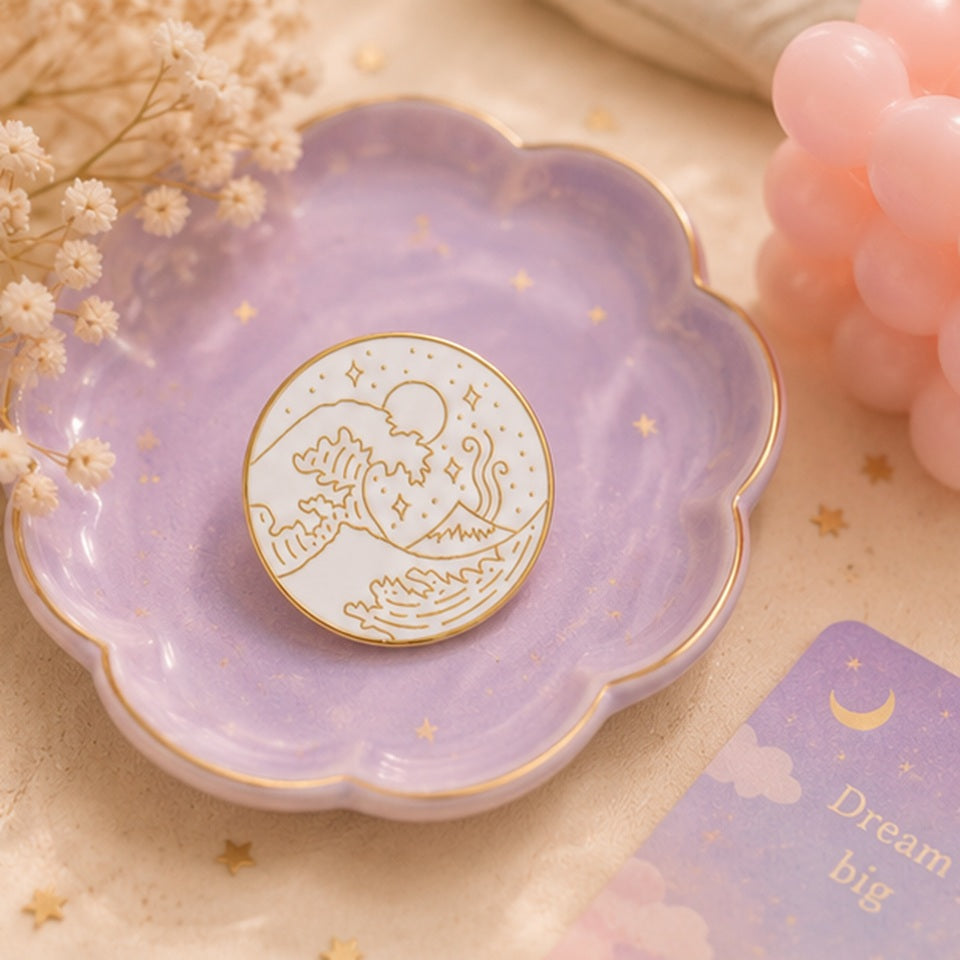 Pin’s vague japonaise minimaliste blanc et doré présenté dans une jolie coupelle violette pastel ✨ Badge élégant inspiré de la Grande Vague de Kanagawa avec détails raffinés représentant les vagues, le mont Fuji et un ciel étoilé. Ambiance douce, poétique et féerique parfaite pour une collection kawaii ou un accessoire japonais chic.