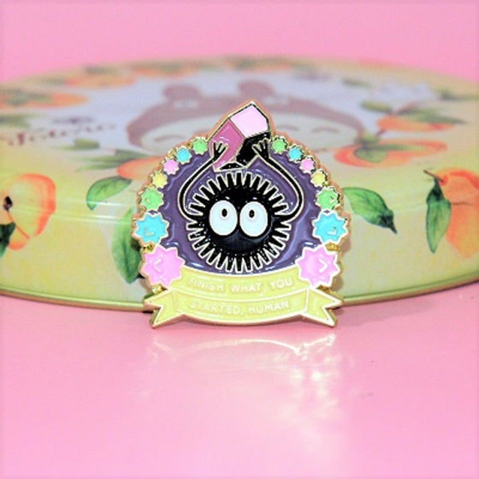 un pin's représentant une noiraude qui soulève un morceau de charbon trop lourd pour elle. Symbole de force, de confiance en soi.