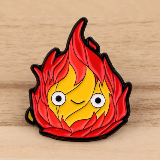 un adorable pin's en forme de calcifer du château ambulant. Expression du visage souriante et trop kawaii. 